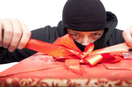 A male in an hat with his face covered opening a present